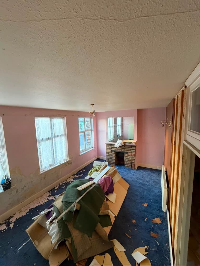 Living room before AHRK refurbishment, with worn carpet and stripped surfaces